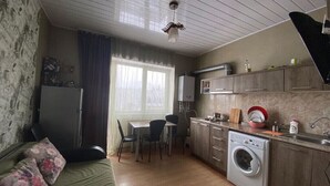 Un espacio habitable compacto con kitchenette, lavadora, zona de comedor y cama.