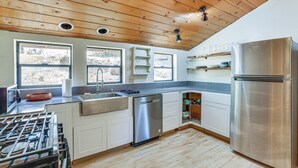 Een moderne keuken met houten plafond, roestvrijstalen apparatuur en grote ramen.