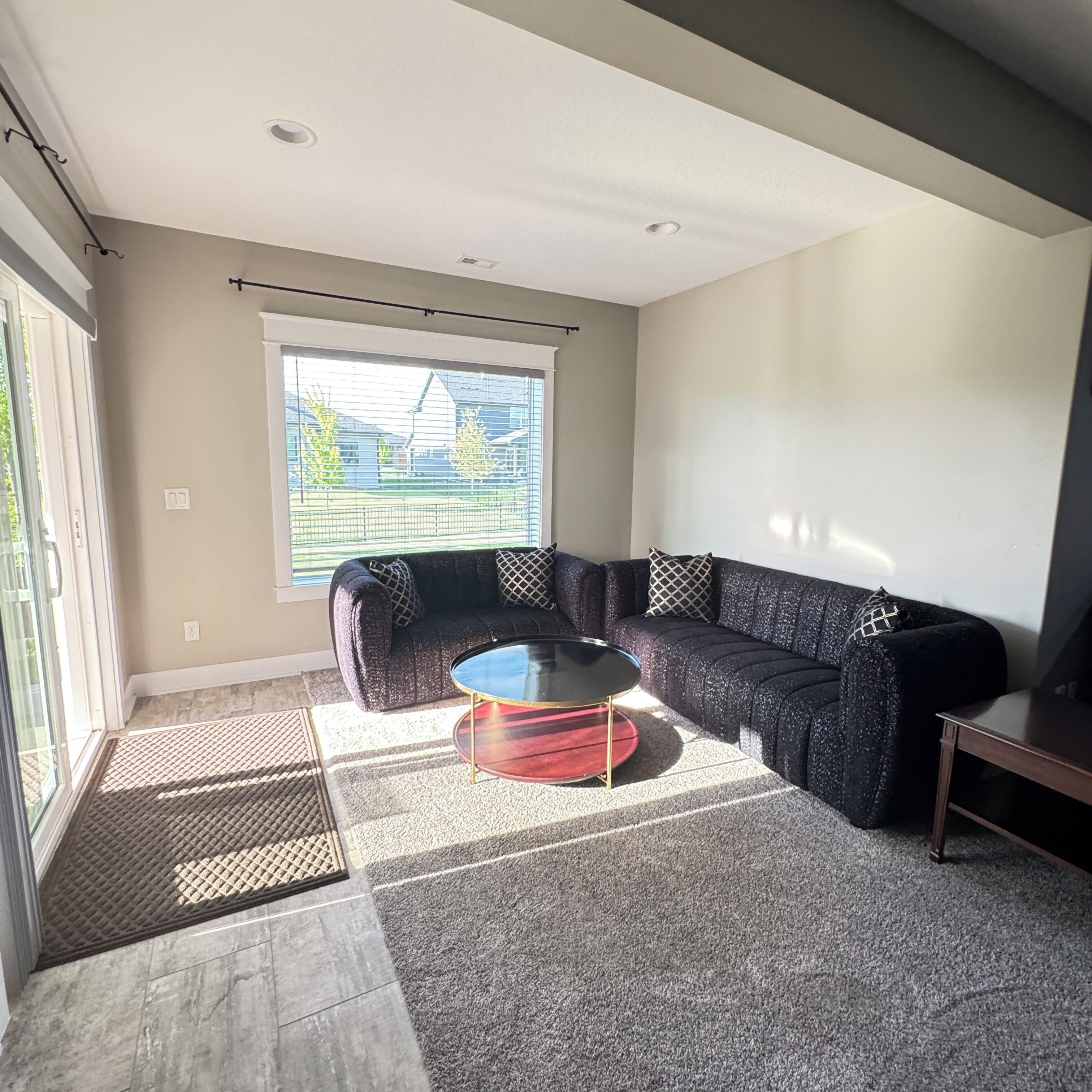 A living room with a sectional sofa, a glass coffee table, and a small side table.