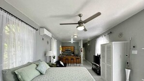 A bedroom with a bed, a ceiling fan, and a kitchenette in the background. - Charming 1-bedroom apartment with Breathtaking views in Ocho Rios, Jamaica (Ocho Rios)