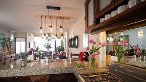 A kitchen with granite countertops, a gas stove, wooden cabinets, and pendant lighting.