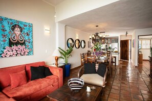 A living room with a red sofa, a dining area with a wooden table, and a kitchen in the background.
