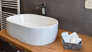 Un baño moderno con un lavamanos grande de color blanco, un espejo encima y una encimera de madera.