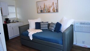 A compact living space with a sofa bed, a kitchenette, and a radiator. - Inclinescape#4 (Colorado Springs)