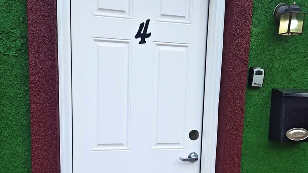 A white door with the number 4, a doorbell, and a mailbox on a green wall. - Inclinescape#4 (Colorado Springs)