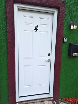 A white door with the number 4, a doorbell, and a mailbox on a green wall.