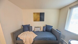 A modern living room with a grey sofa, a beige throw blanket, and a black and gold artwork on the wall. - Inclinescape#3 (Colorado Springs)