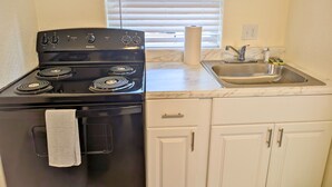 A kitchen with a black stove, a sink, and white cabinets. - Inclinescape#3 (Colorado Springs)