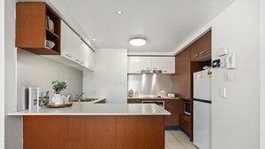 A modern kitchen with a central island, white cabinetry, and stainless steel appliances.