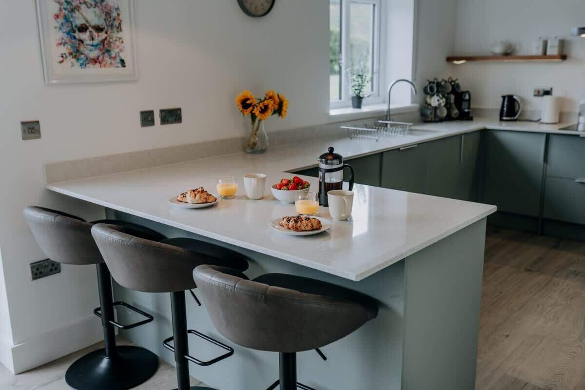 A modern kitchen with a central island, bar stools, and a vase of sunflowers.