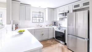 Een moderne keuken met witte kastjes, roestvrijstalen apparatuur en een groot eiland.