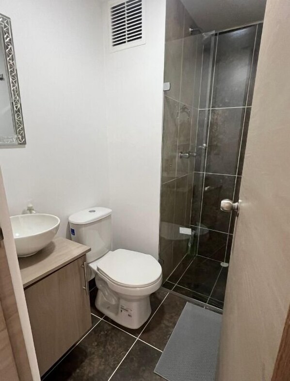 A bathroom with a toilet, sink, and a glass shower enclosure.