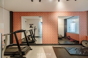 Een fitnessruimte met trainingsapparatuur, een grote spiegel en een metselwerk muur.