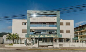 Een hotel genaamd "Portal do Santinho" met een modern design, met een opvallende ingang en meerdere verdiepingen.