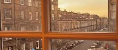 A view through a window of a street scene with buildings, a road, and a bus stop.
