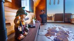 A cozy cabin interior with wooden walls, a large window, a leather sofa, and a cowhide rug.