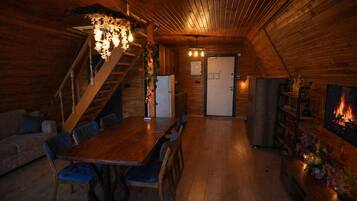 Interior acogedor de una cabaña de madera con comedor, escalera y chimenea.