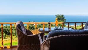 A balcony with wicker furniture overlooking a scenic ocean view. - Galaxy Bungalov (Akçaabat)