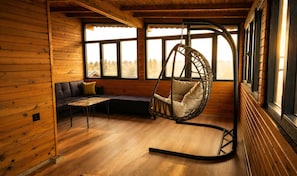 A cozy room with a hanging chair, a sofa, and a table. - Galaxy Bungalov (Akçaabat)