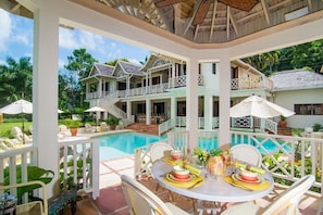 A poolside area with outdoor seating and a dining table set for two.
