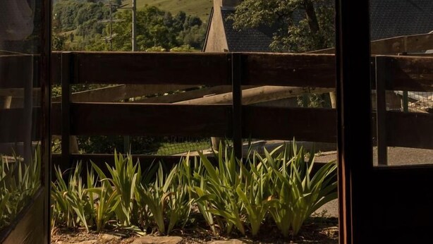 A view from a window with a wooden railing, overlooking a mountainous landscape with green hills and a clear sky. - L'Edelweiss - Poubeau (Poubeau)