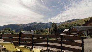 A wooden fence with a bench and yellow chairs in a rural setting with mountains in the background. - L'Edelweiss - Poubeau (Poubeau)