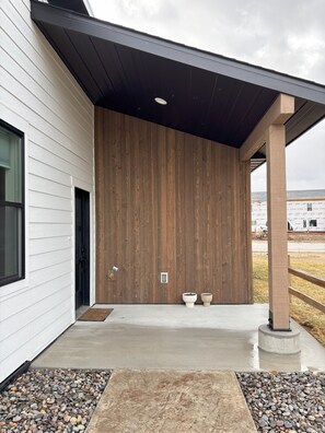 A modern building with a wooden facade, a concrete entrance, and a gravel pathway.