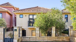 A two-story building with a tiled roof, a balcony, and a gated entrance.