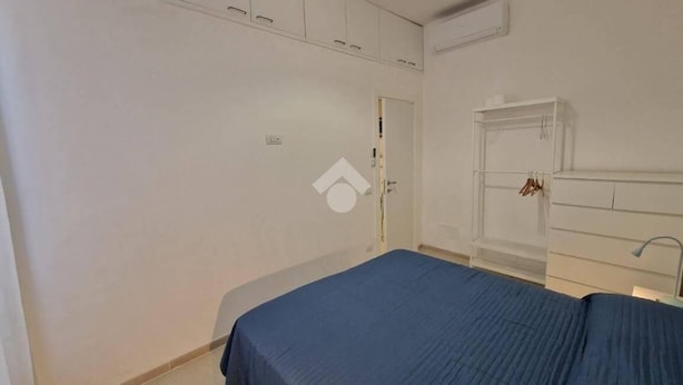 Un dormitorio con cama, armario blanco y una puerta.