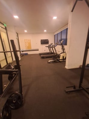 Un gimnasio con cintas de correr, una bicicleta estática y una estructura para sentadillas.