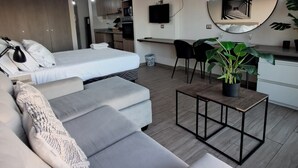 En moderne stue med en sofa, et spisebord med stole, et køkkenområde og et stort spejl på væggen.