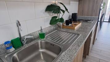 Una cocina moderna con encimera de granito, pileta de acero inoxidable y muebles de madera.