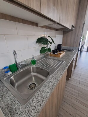 A modern kitchen with a granite countertop, stainless steel sink, and wooden cabinets.