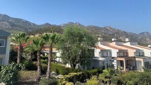 Un barrio residencial con casas modernas, abundante vegetación y montañas al fondo.