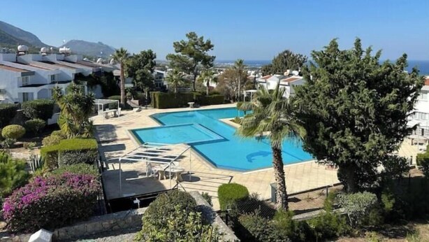 Una piscina con vista al mar, rodeada de vegetación y edificios.