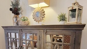 Een houten kast met glazen deuren, een wandlamp en decoratieve objecten erboven.
