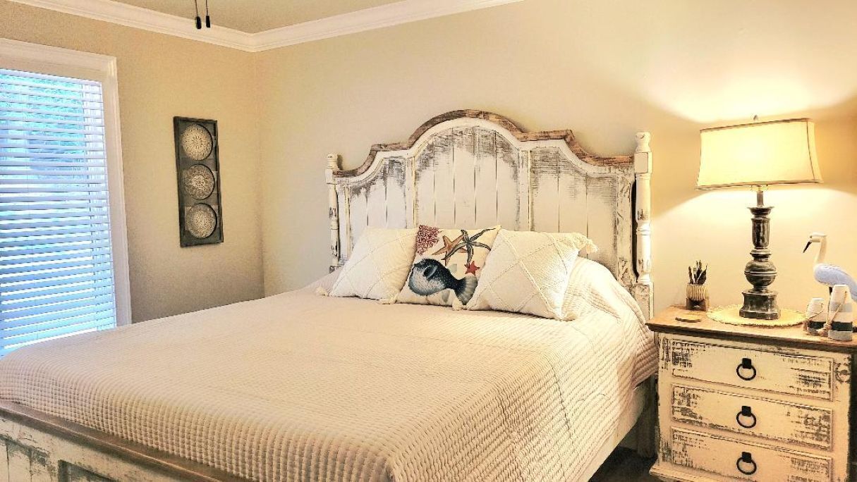 Une chambre à coucher comprenant un lit, une table de chevet, une lampe et un élément décoratif mural.