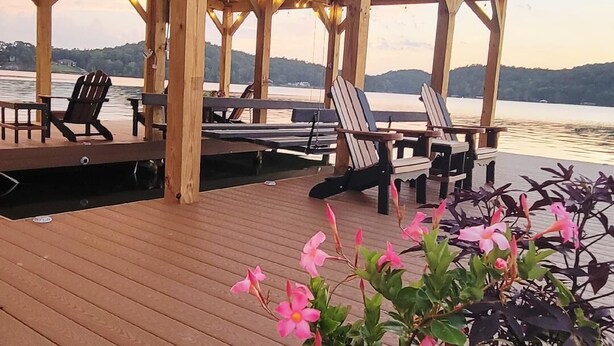 Een houten terras met stoelen en tafels, met uitzicht op een waterpartij.