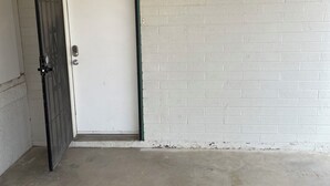A closed door with a metal handle, a white brick wall, and a concrete floor.