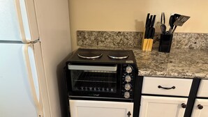 A compact kitchen with a built-in oven and microwave, white cabinets, and a granite countertop.