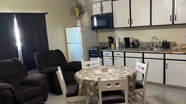 A living room with a dining table, two sofas, and a ceiling fan.
