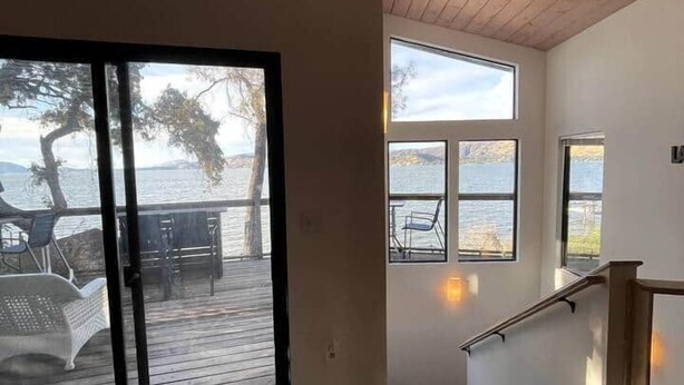 Una habitación con un amplio ventanal corredera que da a una terraza con mobiliario exterior. Varias ventanas ofrecen vistas al exterior.