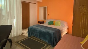 A bedroom with a bed, a chair, a small table, and a dreamcatcher on the wall.