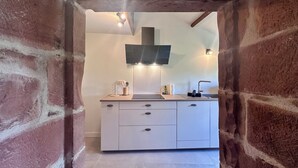 Una cocina de diseño moderno, con un armario blanco, una campana extractora negra y un lavamanos integrado.