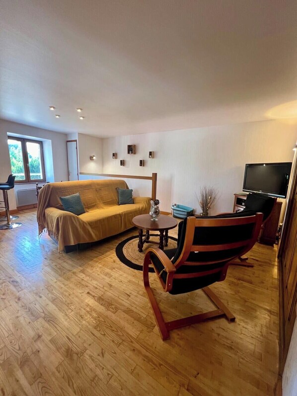 A spacious living room with a sofa, a coffee table, a TV, and a wooden floor.