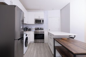 Una cocina moderna con electrodomésticos de acero inoxidable, armarios blancos y una mesa de madera.
