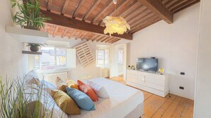 Een slaapkamer met een bed, nachtkastjes, een televisie en een raam.