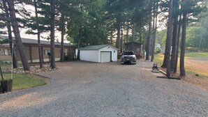A gravel driveway leading to a garage, surrounded by trees and a small shed.