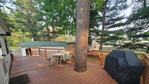 A wooden deck with a picnic table and a barbecue grill.