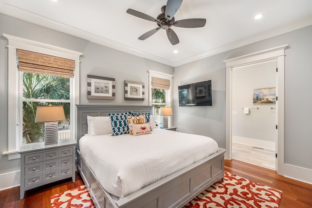 A bedroom with a bed, nightstands, a ceiling fan, and a TV.